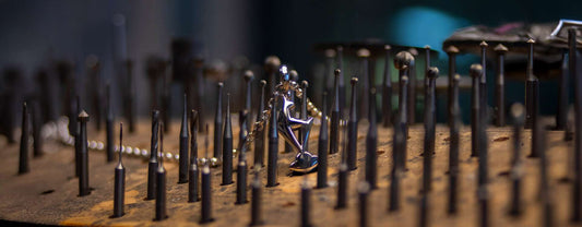 Handgefertigter Gams-Anhänger aus Gold liegt neben traditionellem Juwelier-Werkzeug auf der Werkbank – Symbol für exklusive Tiroler Handwerkskunst und hochwertige Schmuckherstellung bei Juwelier Schroll in Kitzbühel