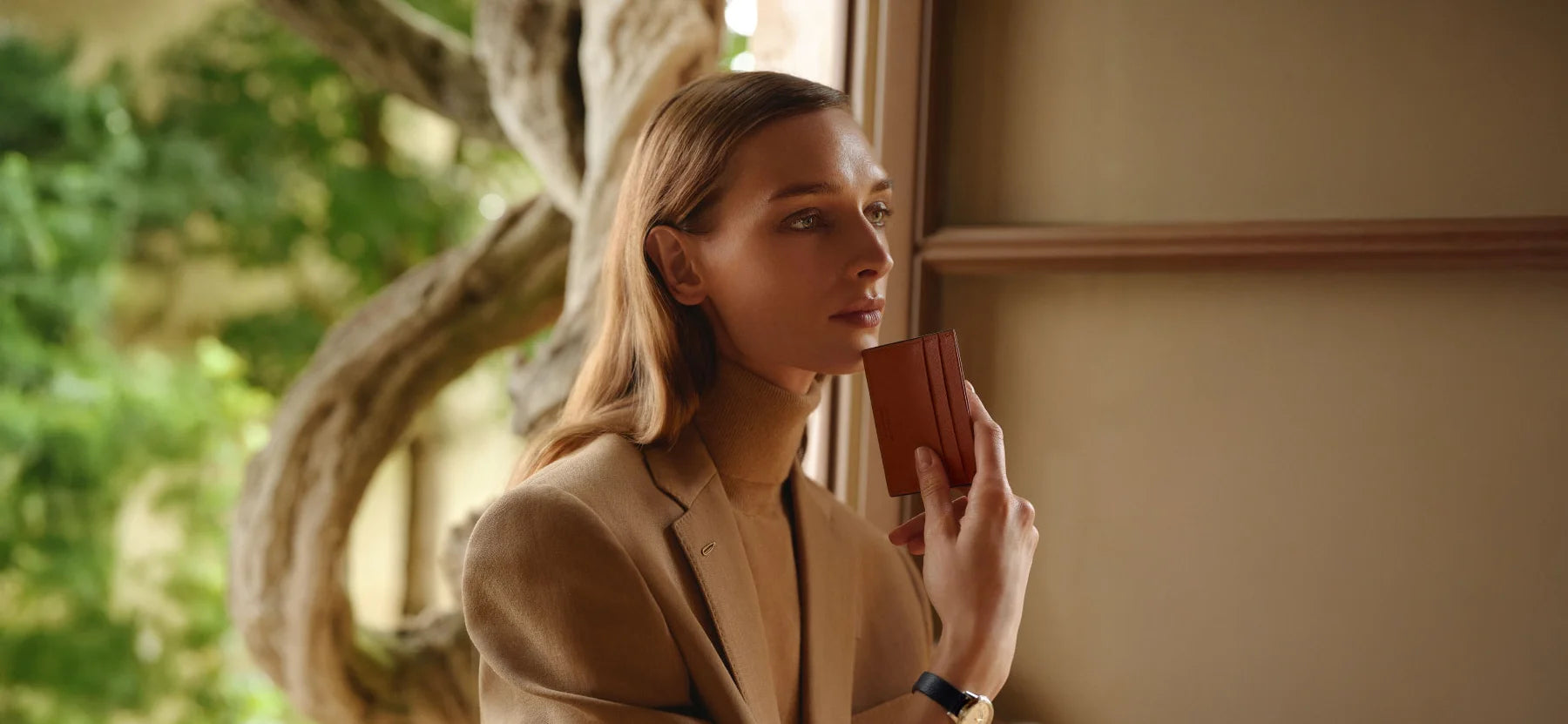 ine stilvolle Frau in beigem Tweed-Sakko präsentiert das Montblanc Meisterstück Kartenetui in British Green. Dieses exklusive Leder-Accessoire ist jetzt erhältlich im juwelier-tirol.shop.