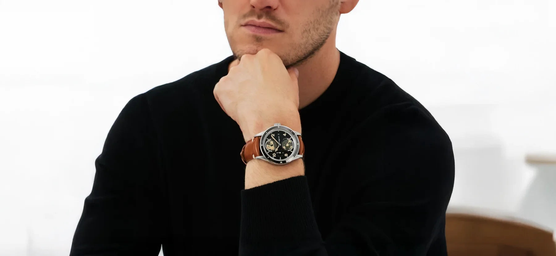 Nahaufnahme der luxuriösen Montblanc 1858 Geosphere Armbanduhr mit markanter Weltzeit-Komplikation und braunem Lederarmband, getragen von einem Mann im schwarzen Pullover. Erhältlich im juwelier-tirol.shop.
